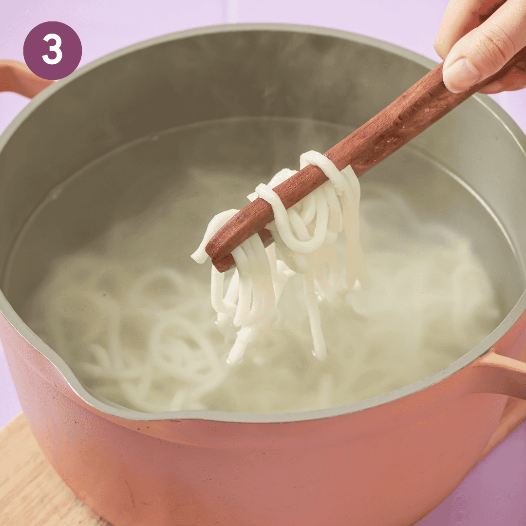 udon noodles cooking in a pot of water.
