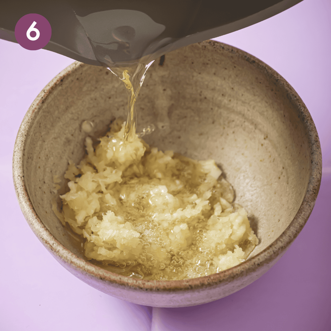 person pouring hot oil over garlic in the bowl.