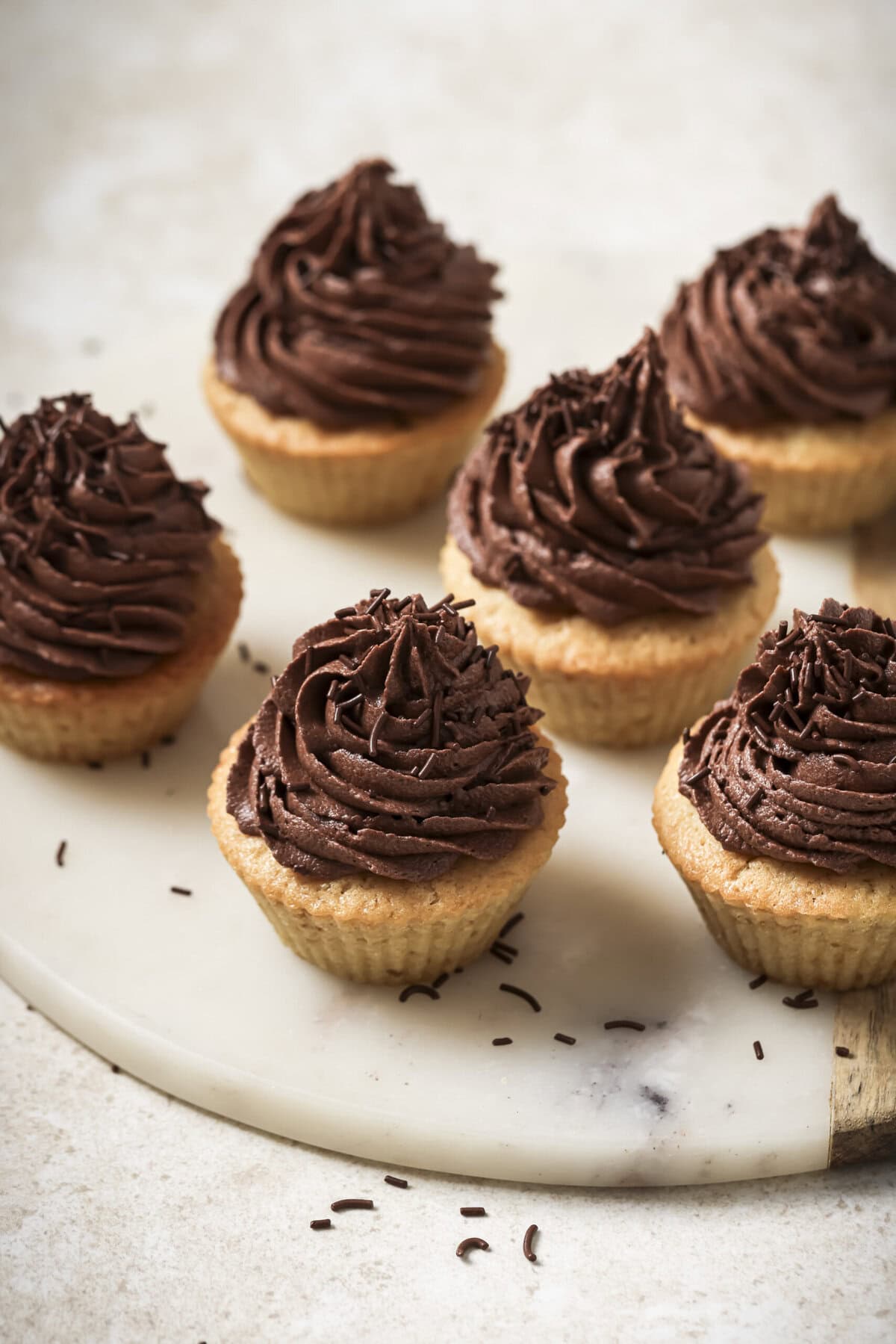 45 degree downward angle view of 6 cupcakes on a marble serving tray.