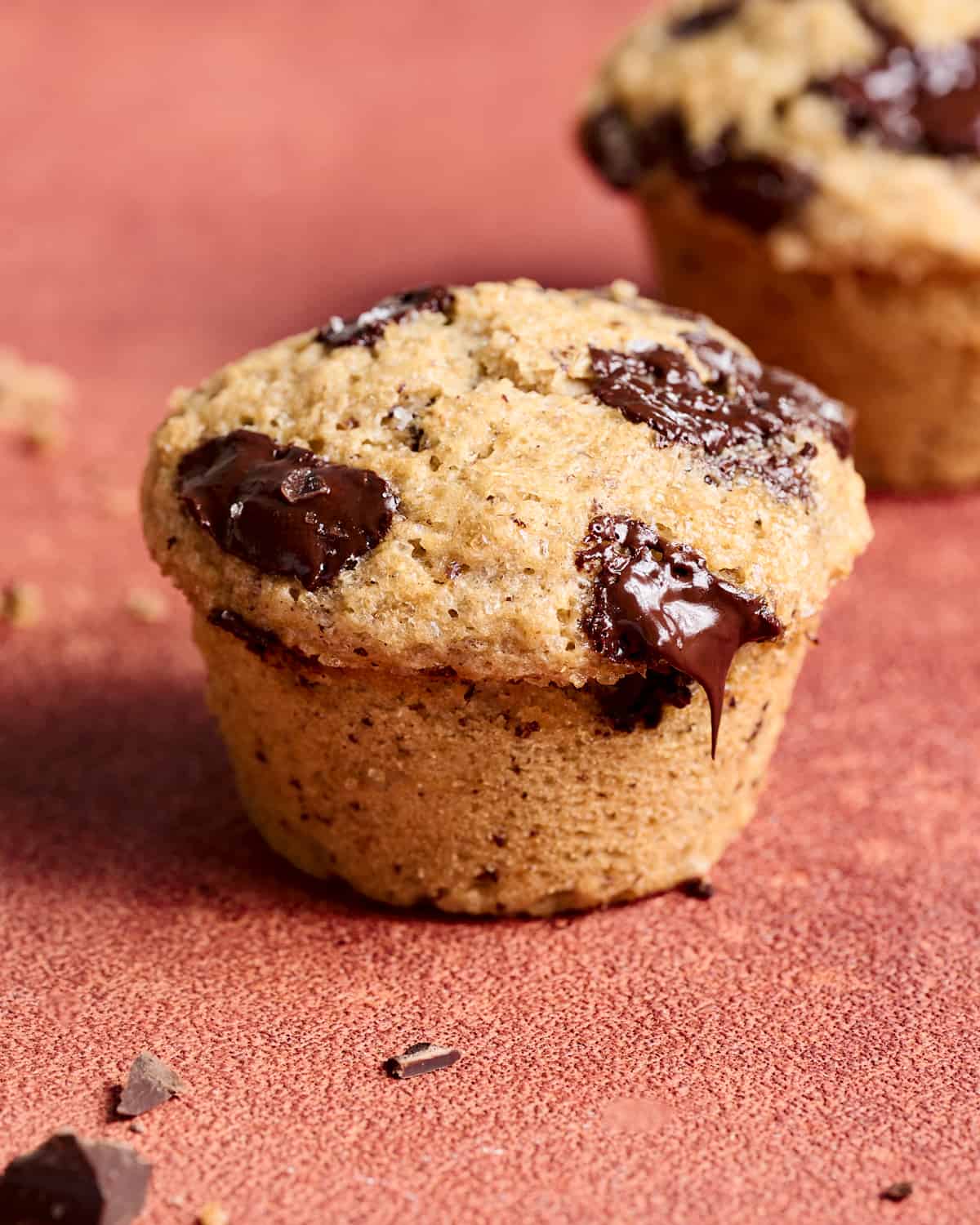 Close up of one full muffin on a red table.