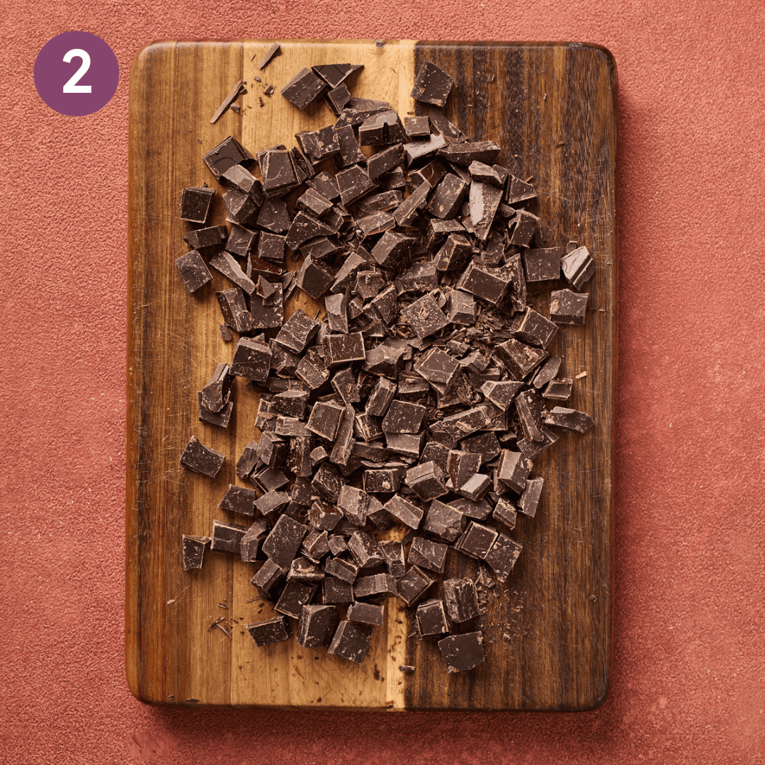 Chopped chocolate on a wooden cutting board.