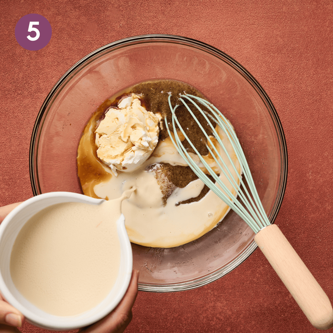 person whisking vegan buttermilk into bowl with vanilla extract and sour cream.