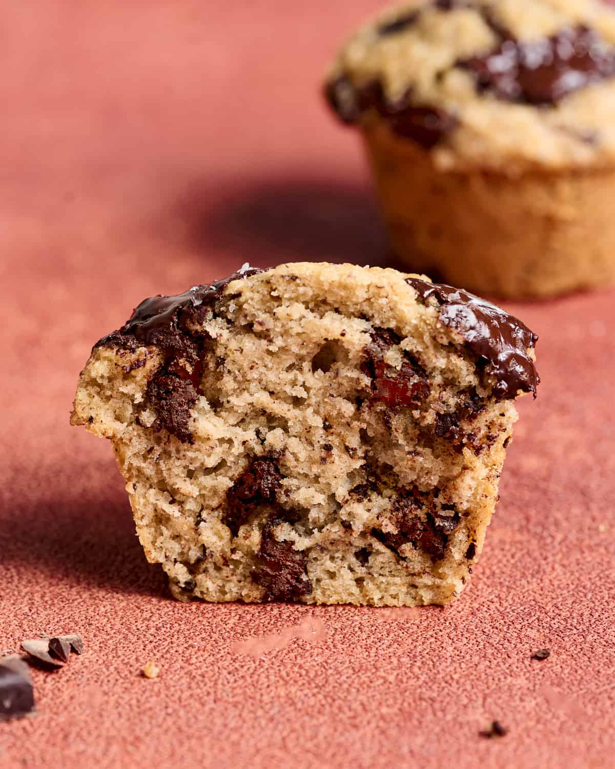 Close up of half a muffin on a red table.